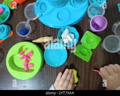 Il bambino modella la plastica morbida, gioca al tavolo con una serie di stampi e un coltello. Giochi educativi. Foto Stock