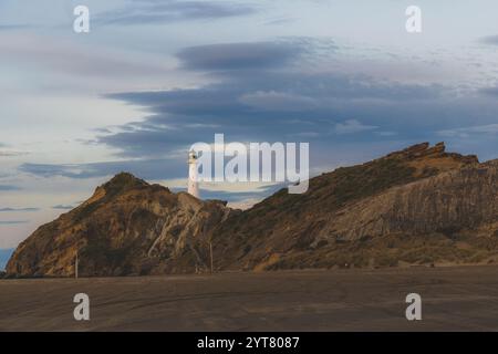 Il faro di Castlepoint sull'Isola del Nord della nuova Zelanda sorge su una spiaggia sabbiosa tra le rocce. La torre bianca è il punto di riferimento della piccola città sulla costa orientale. Foto Stock