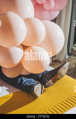 Le gambe inferiori dell'uomo sono coperte da palloncini rosa chiaro Foto Stock