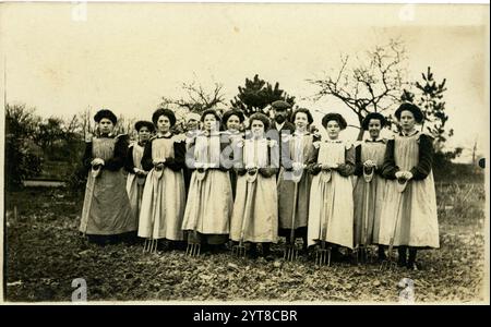 Cartolina edoardiana originale di giovani donne, che tengono forchette, imparano le abilità orticole, forse al college orticolo come Studley, c 1908 -1910 a causa dell'acconciatura. Foto Stock