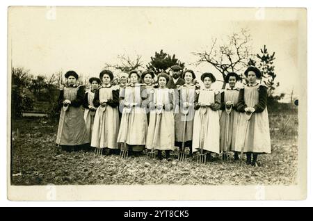 Cartolina edoardiana originale di giovani donne, che tengono forchette, imparano le abilità orticole, forse al college orticolo come Studley, c 1908 -1910 a causa dell'acconciatura. Foto Stock