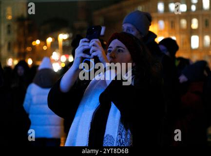 KIEV, UCRAINA - 6 DICEMBRE 2024 - Una donna scatta foto del principale albero di Natale dell'Ucraina durante la cerimonia di illuminazione in Piazza Sofiiska, Kiev, capitale dell'Ucraina. Foto Stock