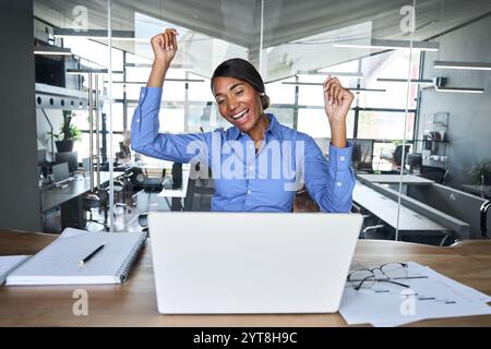 Felice eccitato imprenditore africano dirigente che celebra il successo in ufficio. Foto Stock