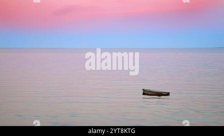 Piccola barca singola su un lago calmo Foto Stock