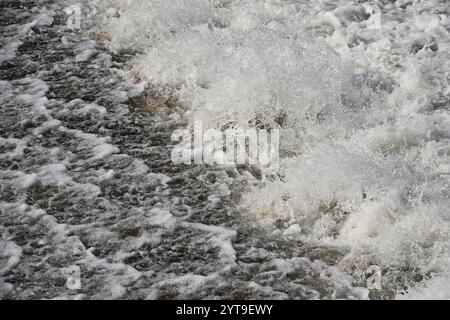 Schiumosità e spruzzi d'acqua su una parete di weir Foto Stock