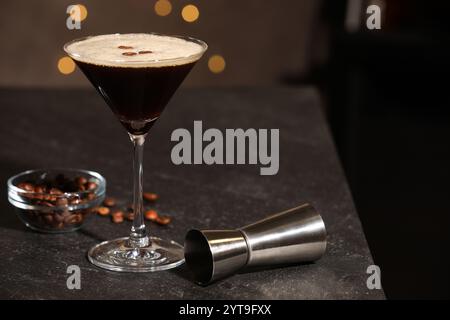 Bicchiere con deliziosi martini espresso, chicchi di caffè e jigger sul tavolo del bar. Spazio per il testo Foto Stock