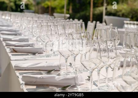 Tavolo da sposa servito con piatti, sedie bianche, tovaglioli e bicchieri da vino Foto Stock