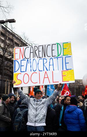 Parigi, Francia. 5 dicembre 2024. Un manifestante ha in mano un cartello che dice "in assenza di democrazia sociale” durante la manifestazione della funzione pubblica francese. Circa 200.000 persone hanno manifestato in tutta la Francia, secondo la CGT (Confederazione generale del lavoro) in un giorno di scioperi del servizio civile, nonostante la caduta del governo francese a causa del voto su una mozione di censura in seno all'Assemblea nazionale. A Parigi, circa 3.000 persone hanno preso parte alla manifestazione per chiedere maggiori risorse per il servizio pubblico e per avvertire del '' deterioramento˜' delle loro ''˜condizioni di lavoro e payâ (C Foto Stock