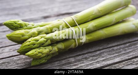 Asparagi freschi verdi su tavole rustiche di legno grigio. Primo piano con profondità di campo ridotta. Sfondo per una gastronomia sana con spazio per il testo. Foto Stock