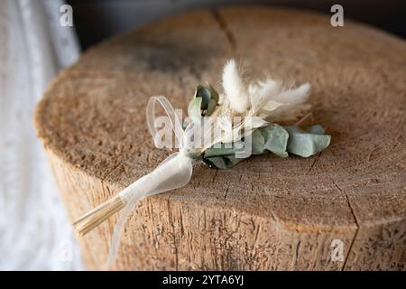 Boutonniere di sposo in stile boho su legno rustico. Decorazioni sostenibili per il costume da sposa. Foto Stock