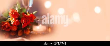 Natura morta con rose rosse e tulipani con un tono di albicocca chiaro e un bokeh lucente. Sfondo festivo orizzontale con champagne e lume di candela per nozze con spazio per testo. Foto Stock