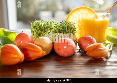 Uova di Pasqua e crescione fresco decorati su un tavolo di legno per una sana colazione pasquale con succo d'arancia. Foto Stock