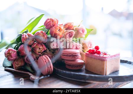 Bellissimo bouquet di fiori rosa con dolci prelibatezze. A forma di cuore, dolci dolci con rose rosa e tulipani su un tavolo di legno. Sfondo per la festa della mamma e i matrimoni. Foto Stock