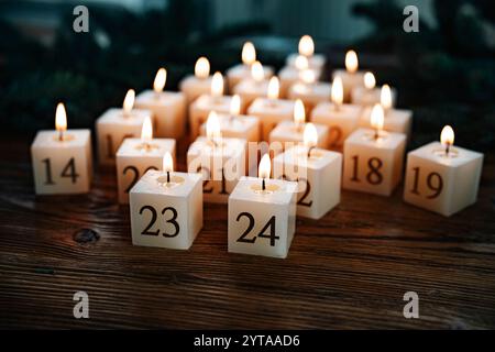 Bruciare le candele a natale. Candele fatte in casa per l'avvento fatte in cera d'api naturale. Decorato a forma di albero di natale su legno scuro. Sfondo natalizio con breve profondità di campo. Foto Stock