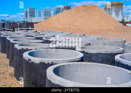 Tubi per fognature in cemento armato grandi diametri di cantieri impilati di grande diametro, sabbia e ghiaia a pelo successivo, materiale di drenaggio per costruzioni in violazione Foto Stock