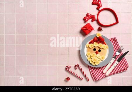 Piatto con pancake a forma di Babbo Natale su sfondo piastrellato rosa Foto Stock