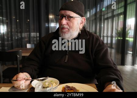 L'anziano si siede in un ristorante e mangia il suo pasto. Sembra serio Foto Stock