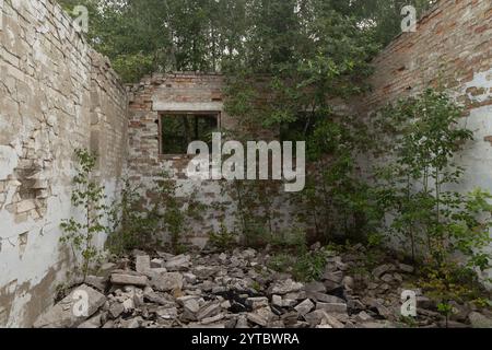 Un vecchio edificio crollato nella base dell'esercito sovietico in Lettonia, in Europa. Edificio abbandonato in mattoni bianchi. Foto Stock