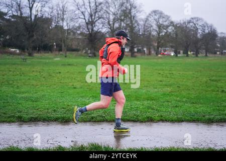 Londra, Regno Unito. 7 dicembre 2024 Un jogger a Wimbledon comune come Storm Darragh colpisce il Regno Unito con forti piogge e raffiche di vento superiori ai 60 km/h il Met Office emette avvisi meteo rossi e gialli come Storm Darragh con condizioni di guida difficili, chiusure del Royal Park, ritardi di viaggio e inondazioni. Credito. Amer Ghazzal/Alamy Live News Foto Stock