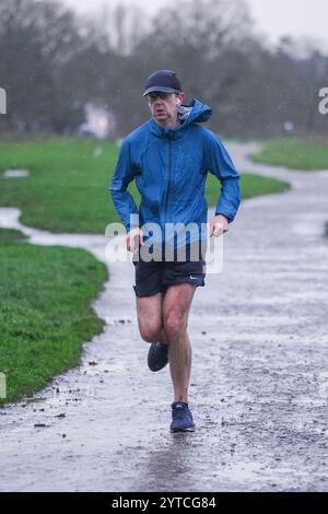 Londra, Regno Unito. 7 dicembre 2024 Un jogger a Wimbledon comune come Storm Darragh colpisce il Regno Unito con forti piogge e raffiche di vento superiori ai 60 km/h il Met Office emette avvisi meteo rossi e gialli come Storm Darragh con condizioni di guida difficili, chiusure del Royal Park, ritardi di viaggio e inondazioni. Credito. Amer Ghazzal/Alamy Live News Foto Stock