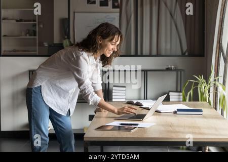 Giovane donna professionale sorridente che lavora su un notebook Foto Stock