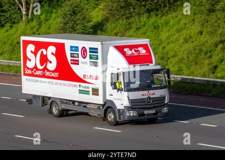 Furgone SCS. Un camion rigido Actros Mercedes-Benz specializzato in divani e moquette; viaggia sull'autostrada M6, Regno Unito Foto Stock