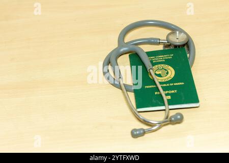 documento di viaggio internazionale nigeriano con stetoscopio su tavolo biondo Foto Stock