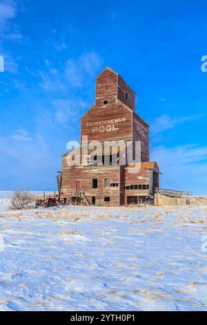 Un grande, vecchio silo di grano abbandonato con un cartello. Il silo è circondato dalla neve e si trova in una zona desolata e abbandonata Foto Stock