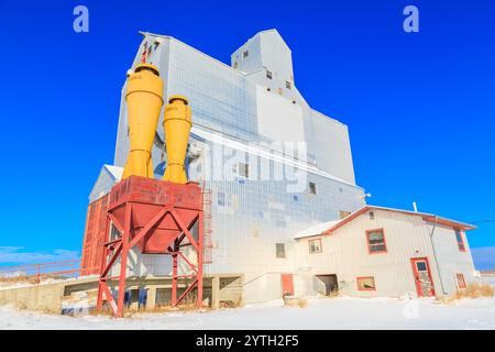 Un silo a grana grande con due silos arancioni sulla parte superiore. I silos sono vuoti. Il cielo è blu e limpido Foto Stock