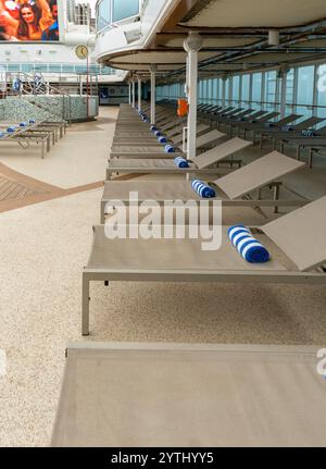 Mare Adriatico - 16 ottobre 2024 Una fila di sedie a sdraio vuote con asciugamani arrotolati ben posizionati attende gli ospiti presso la piscina sul Lido Deck dell'Isola PRI Foto Stock