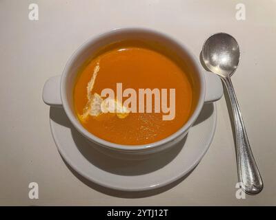 Una confortevole ciotola di zuppa di pomodoro cremosa, servita calda con un turbinio di panna sulla parte superiore, che offre una consistenza ricca e vellutata e un equilibrio di piccante e saporito Foto Stock