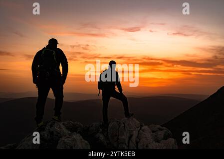 Due viaggiatori che fanno trekking godono di una pausa per ammirare la cima della montagna rocciosa durante l'escursione. Viaggi avventurosi Foto Stock