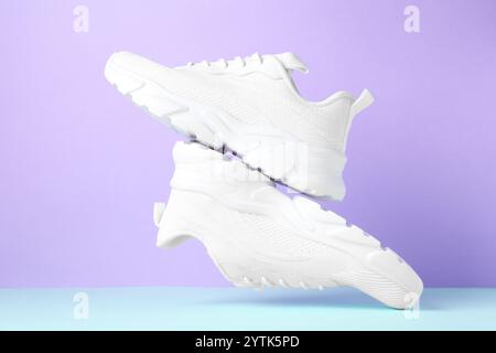 Un paio di eleganti sneaker bianche con aria su sfondo colorato Foto Stock