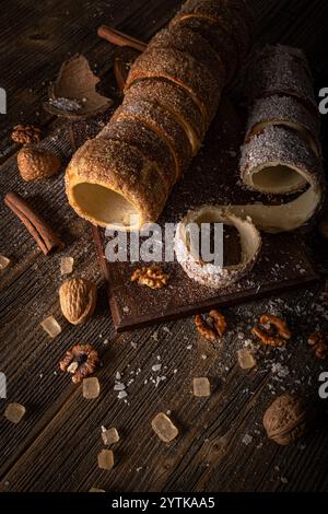 Torta di camino su un rustico asse di legno, guarnita con noci, cannella e caramelle di roccia Foto Stock