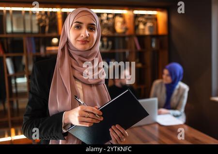 Ritratto di una donna d'affari musulmana felice davanti al team di lavoro in ufficio. Foto Stock