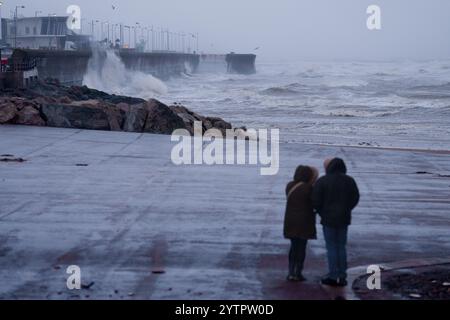 (241208) -- NEW BRIGHTON, 8 dicembre 2024 (Xinhua) -- le persone guardano le onde durante la tempesta Darragh a New Brighton vicino a Liverpool, in Gran Bretagna, 7 dicembre 2024. Decine di migliaia di case sono rimaste senza energia elettrica, i viaggi ferroviari e aerei hanno subito interruzioni e gli eventi sportivi sono stati annullati in tutto il Regno Unito sabato a causa della tempesta Darragh. Un raro avvertimento rosso per il vento, emesso dal Met Office, è in vigore per l'Inghilterra sud-occidentale e il Galles fino a mezzogiorno di sabato, indicando un potenziale pericolo per la vita a causa delle condizioni meteorologiche avverse. Su altre parti sono presenti anche diversi avvertimenti gialli e gialli per vento e pioggia Foto Stock