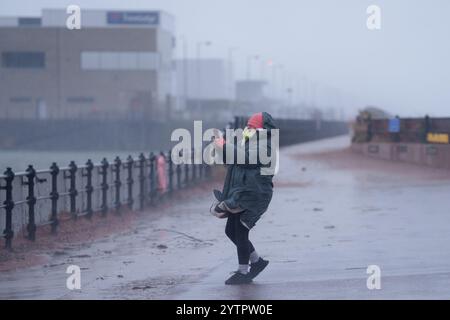 (241208) -- NEW BRIGHTON, 8 dicembre 2024 (Xinhua) -- Un pedone scatta foto durante la tempesta Darragh a New Brighton vicino a Liverpool, Gran Bretagna, 7 dicembre 2024. Decine di migliaia di case sono rimaste senza energia elettrica, i viaggi ferroviari e aerei hanno subito interruzioni e gli eventi sportivi sono stati annullati in tutto il Regno Unito sabato a causa della tempesta Darragh. Un raro avvertimento rosso per il vento, emesso dal Met Office, è in vigore per l'Inghilterra sud-occidentale e il Galles fino a mezzogiorno di sabato, indicando un potenziale pericolo per la vita a causa delle condizioni meteorologiche avverse. Diversi avvisi gialli e gialli per vento e pioggia sono presenti anche sull'altro lato Foto Stock