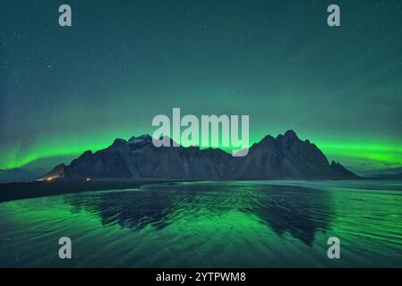 L'aurora boreale si riflette nelle sabbie umide di Vestrahorn, Islanda. Foto Stock