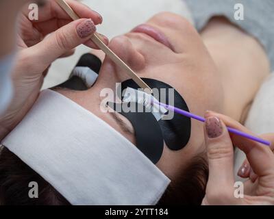 Il master pulisce le ciglia del cliente dal sebo prima delle estensioni. Foto Stock