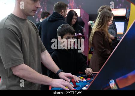 Krasnogorsk, Russia. 1 dicembre 2024. Un ragazzo gioca a videogiochi retrò con gli adulti durante la mostra. RED Expo è la più grande fiera internazionale di intrattenimento interattivo in Russia. Dal 28 novembre al 1° dicembre 2024, riunisce creatori e distributori di videogiochi, produttori di contenuti correlati, cosplayer, appassionati di videogiochi e altri partecipanti al settore del gaming presso il complesso espositivo Crocus Expo. Credito: SOPA Images Limited/Alamy Live News Foto Stock