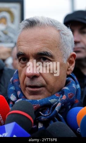 Mogosoaia, Romania. 8 dicembre 2024. Calin Georgescu (front), vincitore del primo turno delle elezioni presidenziali in Romania, parla ai media di fronte a un seggio elettorale chiuso a Mogosoaia, vicino Bucarest, Romania, 8 dicembre 2024. Il candidato presidenziale indipendente Calin Georgescu ha invitato l'Ufficio elettorale centrale (BEC) e l'Autorità elettorale permanente (AEP) della Romania a ignorare la decisione della Corte costituzionale (CCR) che ha annullato le elezioni presidenziali e a consentire il proseguimento del processo di voto. Crediti: Cristian Cristel/Xinhua/Alamy Live News Foto Stock