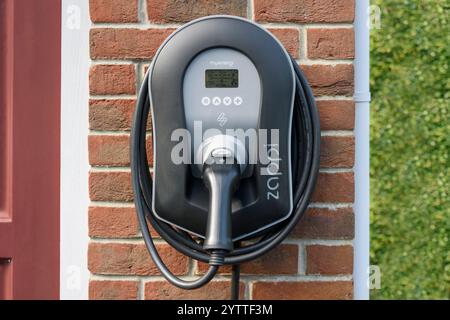 Unità caricabatteria per veicoli elettrici domestici (EV) MyEnergi Zappi montata su una parete in mattoni rossi Foto Stock