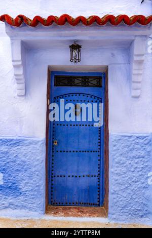 Architettura urbana. Tradizionale porta blu in legno con battitoio rotondo in ferro e borchie. Motivo islamico. Chefchaouen, Marocco, Africa Foto Stock