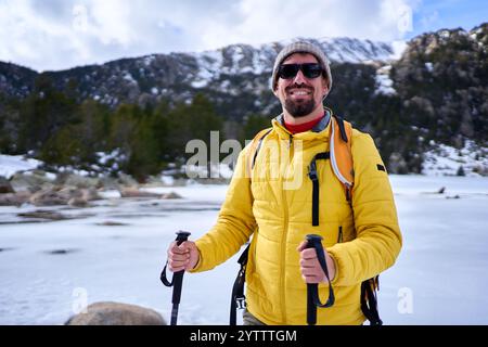 Ritratto di un uomo che guarda la macchina fotografica sorridendo mentre si trova in una montagna innevata. Foto Stock
