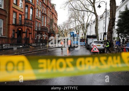 Londra, Regno Unito, 8 dicembre 2024. I chirurghi degli alberi ispezionano un albero caduto. Nelle prime ore della domenica mattina un grande albero allentato da forti piogge e catturato dai forti venti della tempesta Darragh cadde dall'altra parte di una strada di Londra. L'albero di London Plain cadde nell'edificio opposto causando danni al muro anteriore, alle finestre e al tetto. Nessuno si è fatto male. I chirurghi degli alberi sono stati chiamati e rimossi l'albero caduto. Crediti: James Willoughby/Alamy Live News Foto Stock