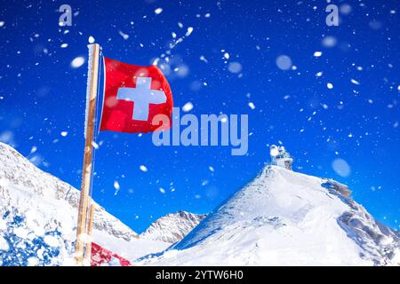 Bandiera svizzera sul picco dello Jungfraujoch e osservatorio della Sfinge vista innevata, regione dell'Oberland Berner in Svizzera Foto Stock