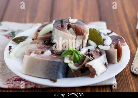 sgombro leggermente salato con cipolle e spezie, in un piatto su un tavolo di legno. Foto Stock