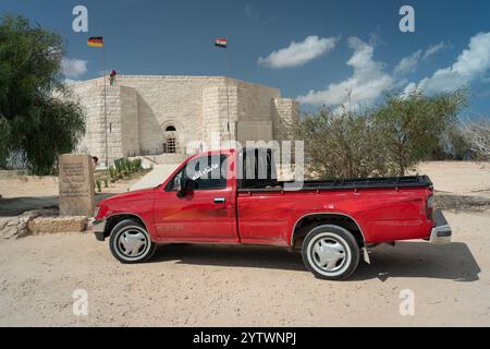 Un pick-up rosso parcheggiato di fronte al cimitero di guerra tedesco di El Alamein. Foto Stock