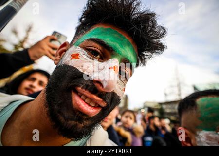 8 dicembre 2024, Renania settentrionale-Vestfalia, Wuppertal: Durante una manifestazione a Wuppertal, un uomo ha dipinto la bandiera siriana sul suo volto. Foto: Christoph Reichwein/dpa Foto Stock