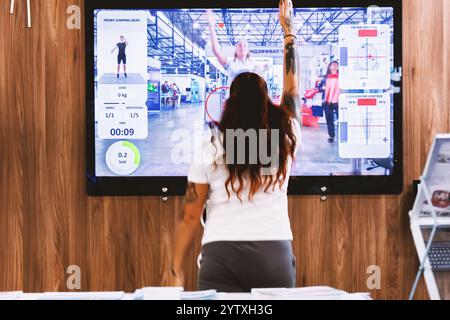 Kiev, Ucraina - 2 ottobre 2024: Una donna si allena utilizzando un sistema televisivo interattivo con feedback. Foto Stock